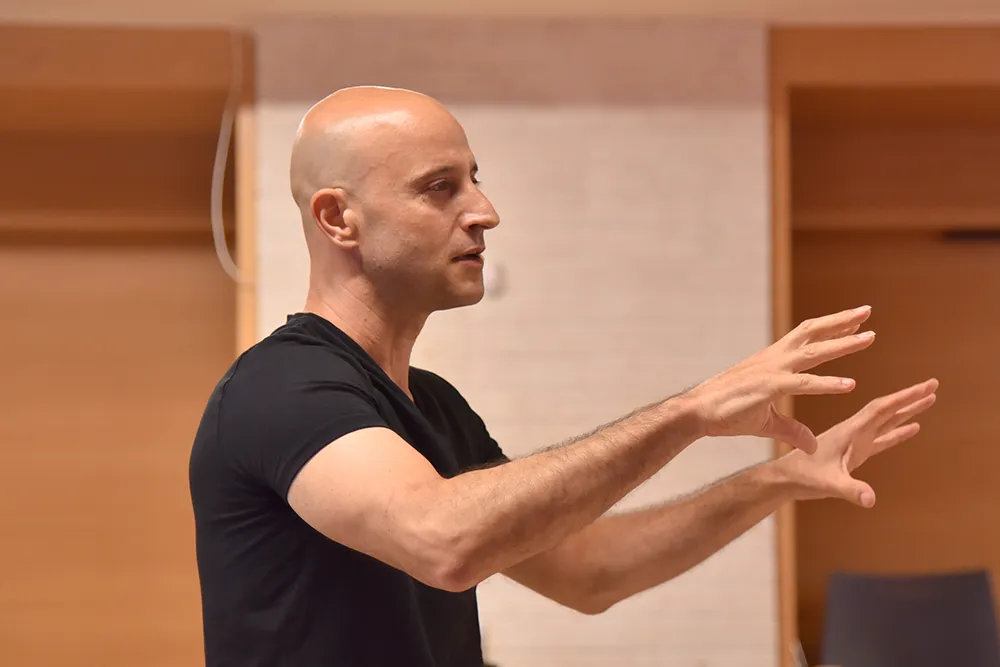 דניאל בעמידה בהרצאה מדגים תנועה משפת גוף